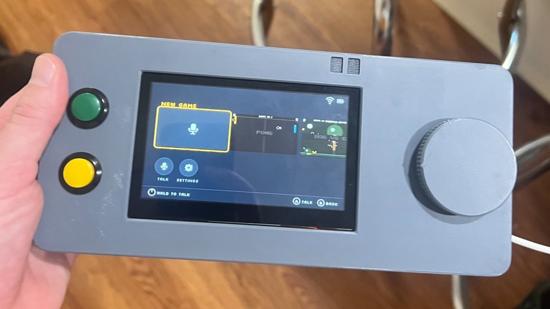 The Fourfold prototype held in one hand: a gray case with a screen in the middle, green and yellow buttons on the left, and a large knob on the right