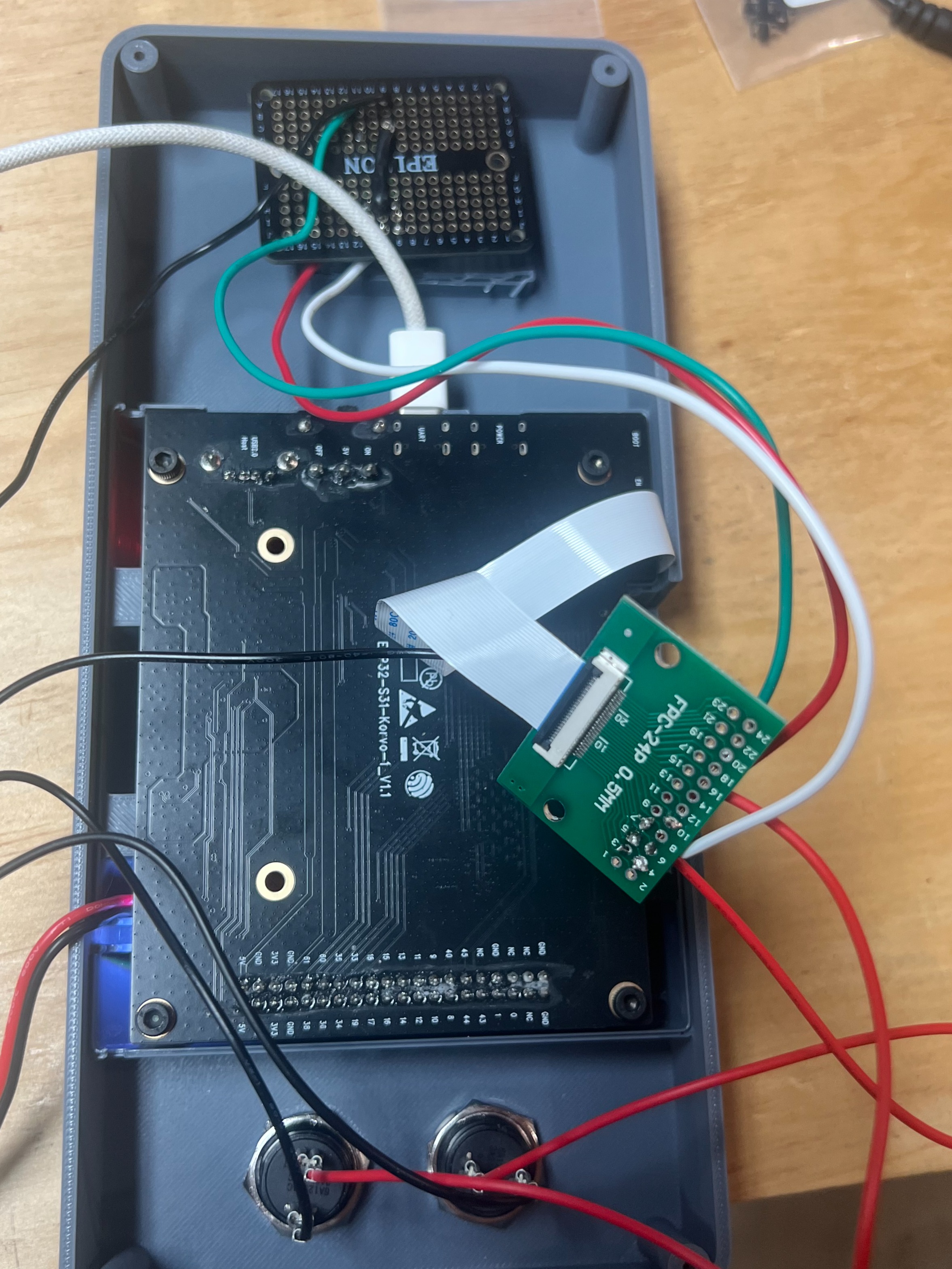 Inside the open case, with the circuit board, a ribbon cable, and wires to the buttons