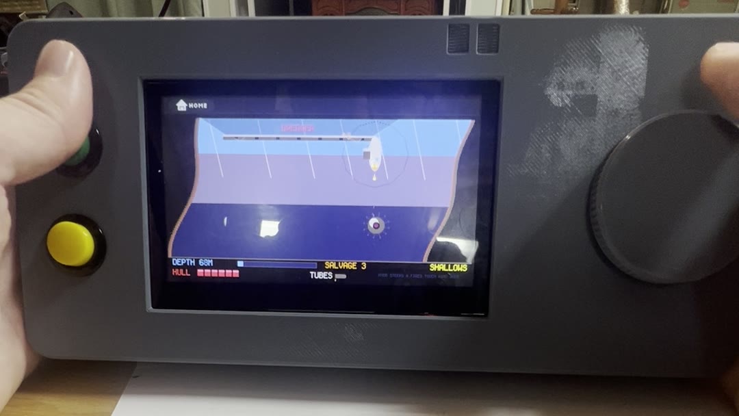The Fourfold prototype in two hands, playing Submarine: a small submarine under a dredger ship, with depth, hull, and salvage readouts along the bottom